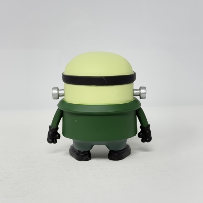 Brinquedo figura de plástico verde e amarelo sobre superfície branca