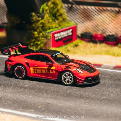 Miniatura de carro desportivo vermelho com detalhes pretos e marcas PIRELLI e Porsche numa pista de corrida.