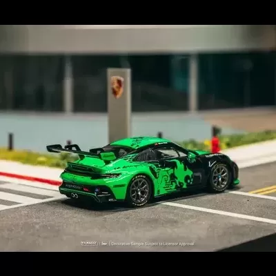Carro desportivo de brinquedo verde com decalques pretos numa rua de miniatura
