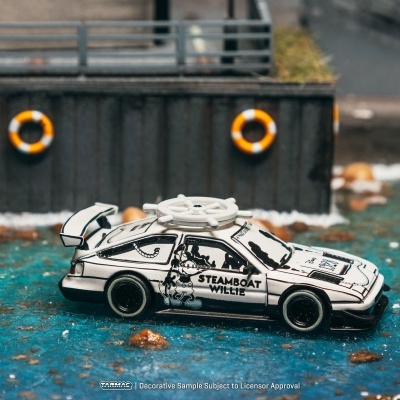 Carrinho de brinquedo branco e preto com volante de barco em cima junto a um cais