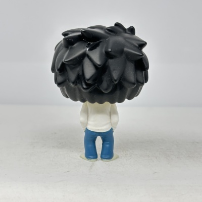 Figura miniatura com cabelos pretos e eriçados, casaco branco e calças azuis, vista de costas