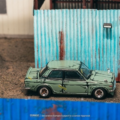 Miniatura de carro clássico verde com autocolantes e parede azul clara corrugada ao fundo