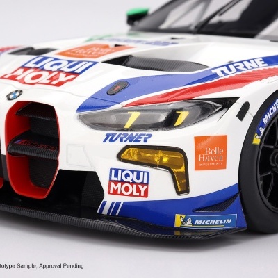 Modelo de carro BMW M4 GT3 branco com logótipos coloridos e faróis amarelos