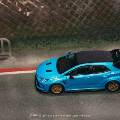 Carro desportivo azul metálico com teto preto e spoiler preto numa estrada com linha vermelha e branca