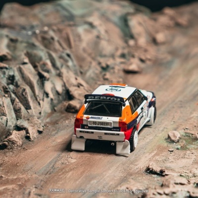 Miniatura de carro de rali em pista de terra com rochas