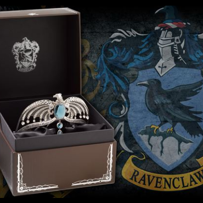 Tiara prateada com pedras azuis e pérolas em caixa castanha com brasão Ravenclaw ao fundo