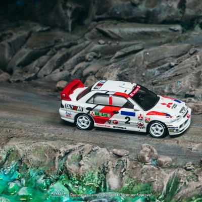 Miniatura de carro de corridas Mitsubishi branco e vermelho em superfície rochosa.