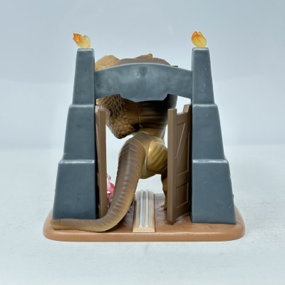 Figura de dinossauro castanho passando por portão cinza com tochas e portas castanhas abertas.