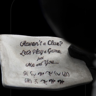 Livro aberto com texto manuscrito em inglês e símbolos, sobre fundo escuro.