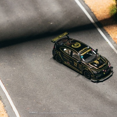 Miniatura de carro de corrida preto com detalhes dourados e número 72 numa estrada de corrida