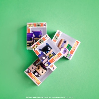 Caixas com figuras Funko Pop Batman sobre fundo verde.