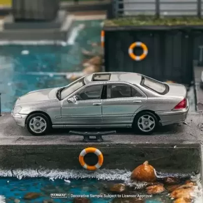 Miniatura de carro prata num cenário urbano com água e salvavidas