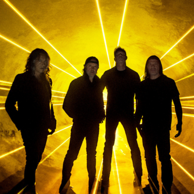 Quatro homens vestidos de preto em silhueta com raios de luz amarelos no fundo