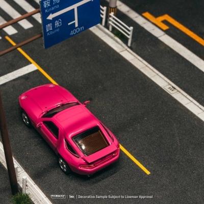 Carro desportivo em miniatura cor fúcsia num modelo de rua com placa azul em japonês