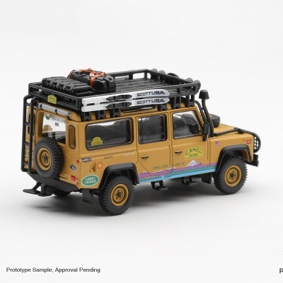 Miniatura Land Rover Defender amarela com decalques Camel Trophy e acessórios de teto pretos
