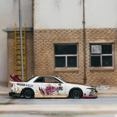 Miniatura de carro desportivo branco com decoração vermelha e dourada em estrada junto a edifício