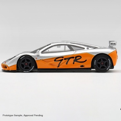 Miniatura de carro desportivo branco e laranja com inscrição GTR e rodas pretas.