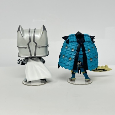 Duas minifiguras de personagens vistas de costas, uma com capacete prateado e capa branca e outra com capa azul texturizada.