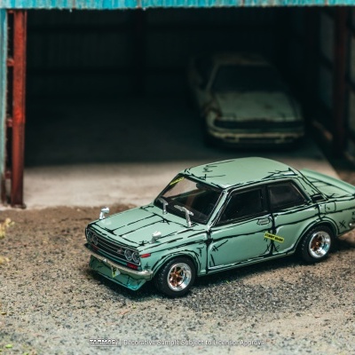 Miniatura de carro clássico verde frente a garagem aberta