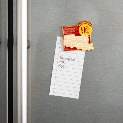 Imã Platform 9 3/4 a prender nota de lista de compras num frigorífico prateado.