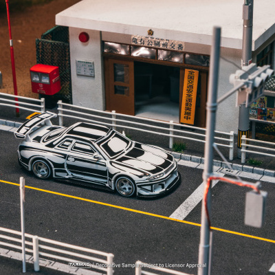 Miniatura de carro de corrida preto e branco em estrada urbana modelada com cabine e sinais em japonês