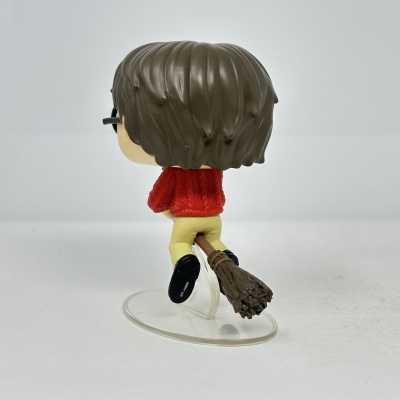 Figura Funko Pop com cabelo castanho e suéter vermelho sentada numa vassoura