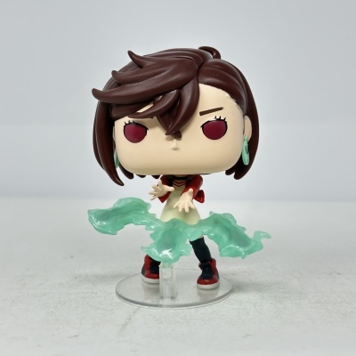 Figura colecionável de vinil com cabelo castanho escuro e olhos vermelhos, com efeitos translúcidos verdes nas mãos.