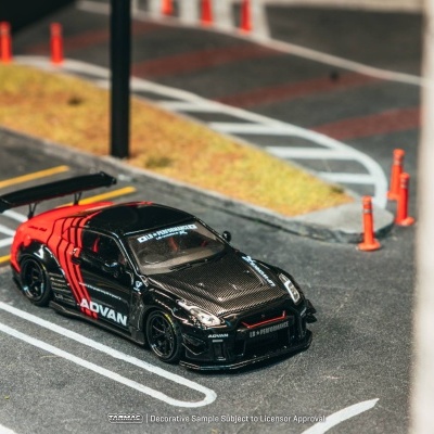 Miniatura de carro de corrida preto e vermelho com textos ADVAN e LB PERFORMANCE numa superfície simulada de estrada