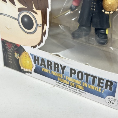 Caixa de figura de vinil Harry Potter com texto e etiqueta de advertência.