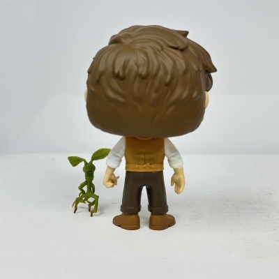 Figura de vinil com cabelo castanho e pequena figura verde tipo planta