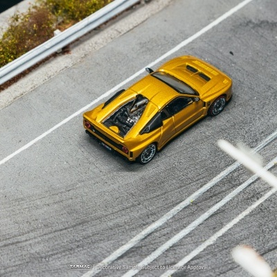 Carro desportivo em miniatura dourado numa pista de corrida em miniatura