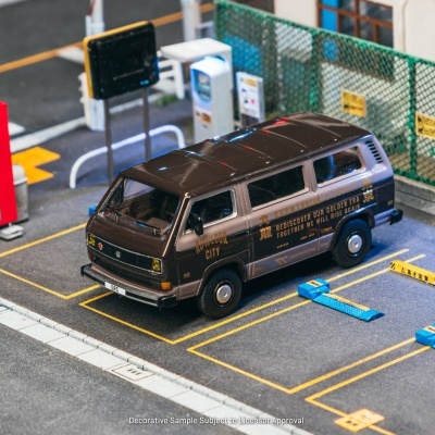 Miniatura de carrinha castanha/bege estacionada em parque em modelo urbano