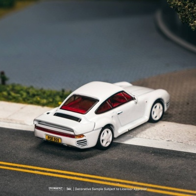 Miniatura de carro branco com janelas vermelhas em estrada junto ao passeio