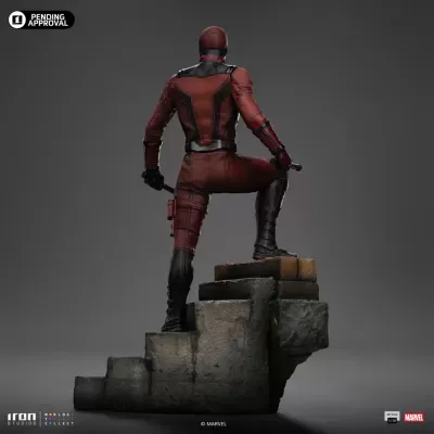 Estátua de personagem vestido de vermelho e preto sobre escada de pedra