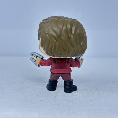 Figura de ação com cabelo castanho e casaco vermelho vista de trás