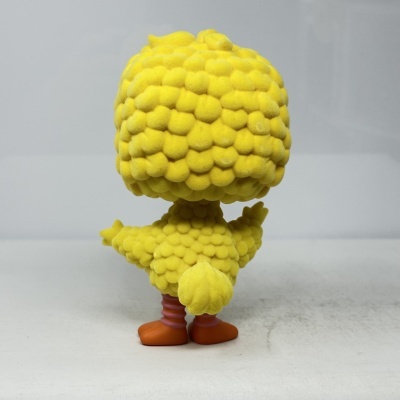 Figura amarela com textura de penas e patas alaranjadas