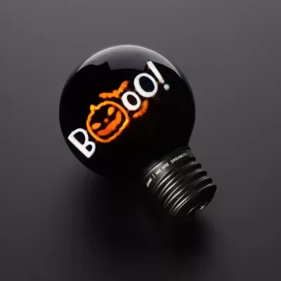 Lâmpada decorativa negra com filamento iluminado a formar Boo! e abóbora laranja.