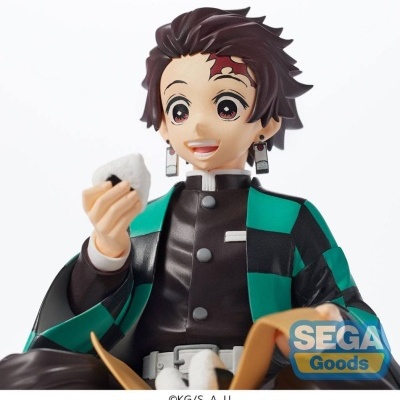 Figura do personagem Tanjiro Kamado em cabelo castanho e casaco preto e verde segurando oniguiri branco.