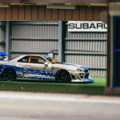 Modelo de carro desportivo azul e branco em cenário de garagem com logo SUBARU