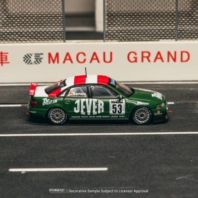 Miniatura de carro de corrida verde com faixa branca e vermelha, número 53 e texto JEVER em pista perto de barreira com MACAU GRAND PRIX