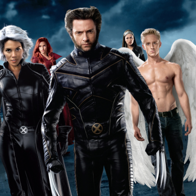 Grupo de personagens em fatos pretos com símbolo X e asas brancas ao fundo nublado