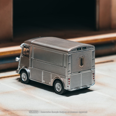 Miniatura de carrinha metálica cinza texturizada em superfície clara com fundo em madeira e metal
