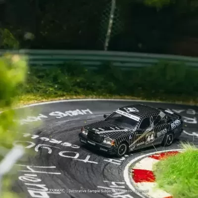 Miniatura de carro de corrida preto com riscas e texto BOSS numa pista curva com relva