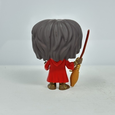 Funko Pop com capa vermelha e vassoura na mão vista de trás