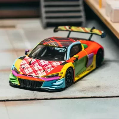 Miniatura de carro desportivo colorido em superfície cinzenta próximo a prateleira de madeira