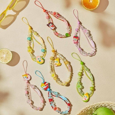 Pulseiras coloridas de contas com pendentes de personagens infantis e etiquetas Baby Molly sobre mesa clara com frutas.