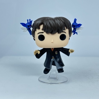 Figura Funko Pop jovem com uniforme preto e duas criaturas azuis com asas brancas ao lado.