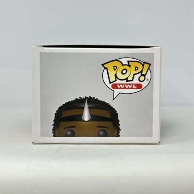 Caixa branca com figura POP! WWE com pele castanha, cabelo preto e coroa prateada