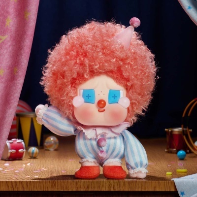 Boneco palhaço com cabelo rosa encaracolado e roupa riscada azul e branca em superfície de madeira