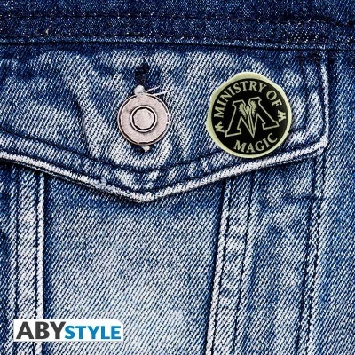 Botão preto e amarelo com texto MINISTRY OF MAGIC na peça de ganga azul com botão metálico